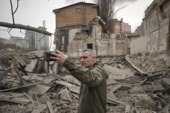 25.03.2024, Ukraine, Kiew: Vitali Klitschko, Bürgermeister von Kiew, macht Fotos am Ort eines russischen Luftangriffs auf den Stadtteil Pechersk. Mehrere Menschen wurden bei dem Angriff verletzt und i ...