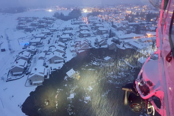 30.12.2020, Norwegen, Oslo: Ein Hubschrauber des Rettungsdienstes fliegt �ber die durch einen Erdrutsch besch�digten H�user. Nach dem Erdrutsch im S�den Norwegens sind mehr als 150 Menschen in Sicherh ...