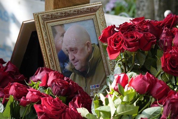 30.08.2023, Russland, St. Petersburg: Ein Porträt des Chefs des Wagner-Konzerns, Jewgeni Prigoschin, der am 23.08.2023 bei einem Flugzeugabsturz ums Leben kam, steht zwischen Blumen auf einem Grab auf ...