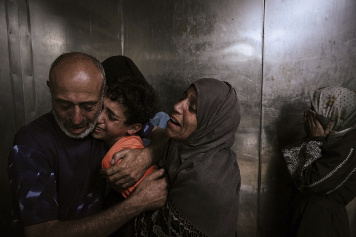 Raed Salem Aslyieh, left, from Jabaliya, hugs his relatives after the death of his son, Ahmed Raed Aslyieh, 18, who succumbed to injuries sustained in an Israeli strike that killed eight other family ...