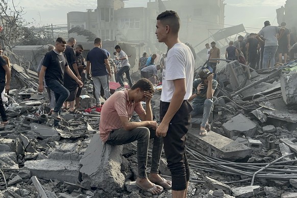 31.10.2023, Palästinensische Gebiete, Nuseirat: Palästinenser suchen nach einem israelischen Luftangriff im Flüchtlingslager Nuseirat im Gazastreifen zwischen den Trümmern eingestürzter Gebäude nach Ü ...