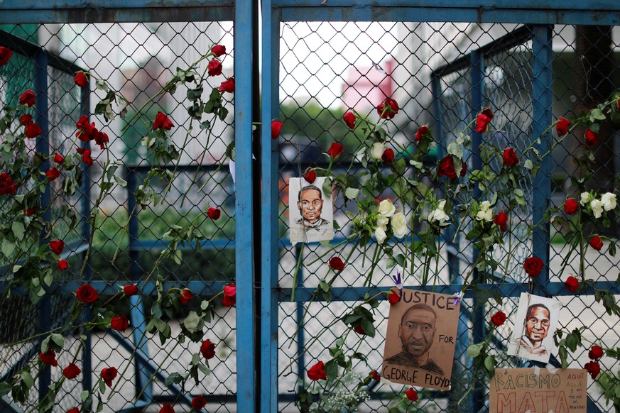 An einem Zaun hängen Bilder und Blumen für George Floyd, der in Minneapolis ums Leben gekommen ist. 