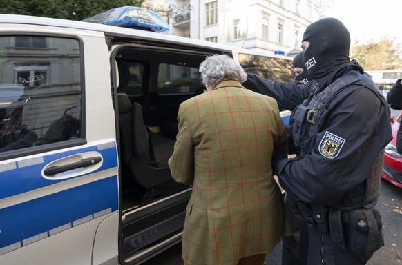 07.12.2022, Hessen, Frankfurt/Main: Bei einer Razzia gegen sogenannte «Reichsbürger» führen vermummte Polizisten, nach der Durchsuchung eines Hauses Heinrich XIII Prinz Reuß (l) zu einem Polizeifahrze ...