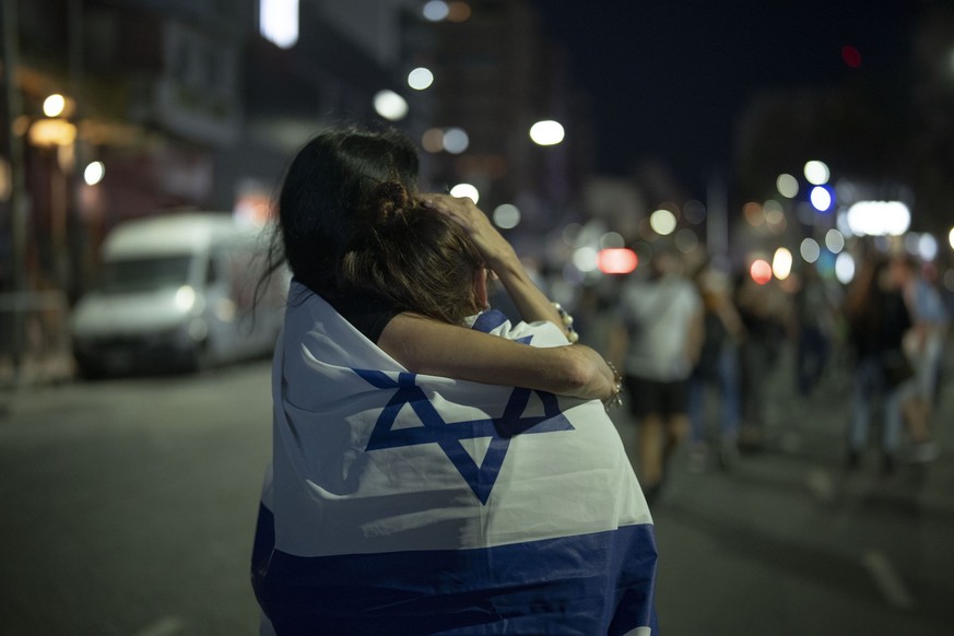 Two persons hug, wrapped in the Israeli flag during a demonstration in support of Israel in Buenos Aires, on Monday, Oct. 9, 2023, after Hamas militants surprised Israel with a deadly attack on Saturd ...