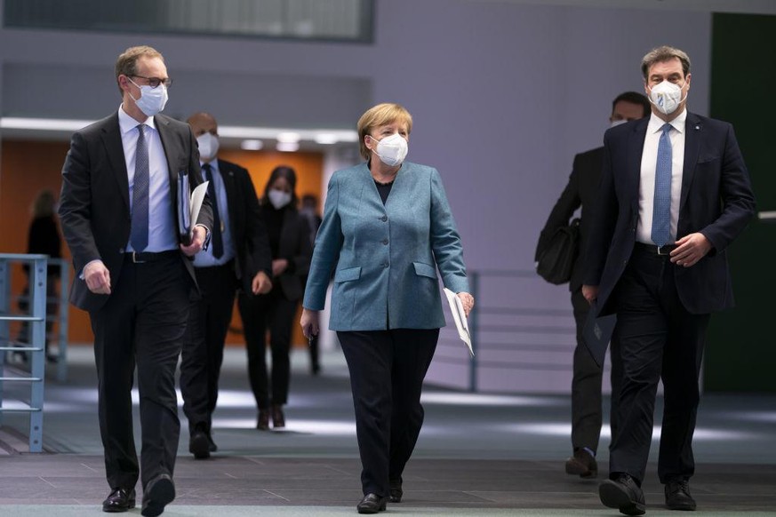 BERLIN, GERMANY - FEBRUARY 01: (L-R) Berlin Mayor Michael Mueller, German Chancellor Angela Merkel and Bavarian Premier Markus Soeder arrive to speak to the media following a video summit between gove ...