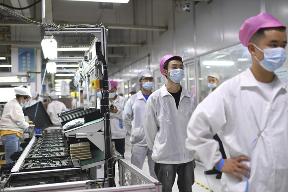 ARCHIV - 05.08.2021, China, Wuhan: Arbeiter stellen sich in der Foxconn-Fabrik in Wuhan an, um sich auf das Coronavirus testen zu lassen. Rund um das gr��te iPhone-Werk der Welt ist es wegen der�strik ...