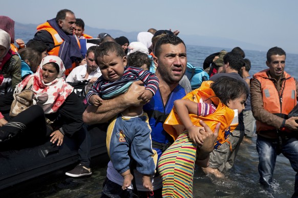 FILE - In this Thursday, Sept. 10, 2015 file photo, Salam Aldeen, from a Copenhagen-based charity organization, carries two babies as Syrian refugees arrive on an overcrowded dinghy after crossing fro ...