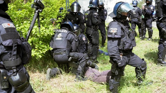 10.05.2024, Brandenburg, Grünheide: Polizisten nehmen einen Aktivisten bei einer Protestaktion gegen Tesla in Gewahrsam. Aktivisten haben am Freitag versucht, auf das Werksgelände von Tesla in Grünhei ...