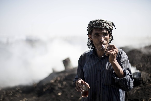 July 11, 2018 - Gaza City, The Gaza Strip, Palestine - Palestinian charcoal worker Mohammed Abu Khater smokes a cigarette as he takes a break at the Al Habbash production facility, east of the Jabaliy ...