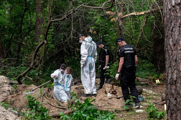 Ausgrabung eines Massengrabes in der Nähe von Bucha Ein Ausgrabungsteam und die Polizei arbeiten in einem Wald in der Nähe von Bucha, Ukraine, um Leichen ukrainischer Zivilisten auszugraben, die von d ...