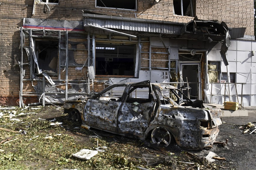 11.08.2024, Russland, Kursk: Ein verbranntes Auto ist vor einem Wohnhaus zu sehen, das nach dem Beschuss durch die ukrainische Seite beschädigt wurde. Foto: Uncredited/AP/dpa +++ dpa-Bildfunk +++