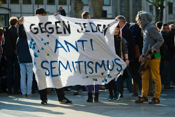 COLOGNE, GERMANY - APRIL 25: Activists holding a banner with the words &quot;Against any kind of anti-Semitism&quot; attend a &quot;wear a kippah&quot; gathering to protest against anti-Semitism in fr ...