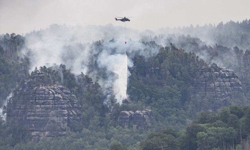 27.07.2022, Sachsen, Schmilka: Ein Hubschrauber der Bundeswehr fliegt mit einem L