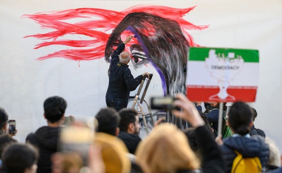 09.11.2022, Berlin: Der deutsch-iranische Künstler Kani Alavi malt ein zwanzig Meter breites und drei Meter hohes Bild von Jina Mahsa Amini an der &quot;East Side Gallery&quot; auf eine Leinwand. Der  ...