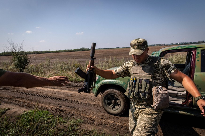 August 19, 2022, Mykolaiv Oblast, Ukraine: Ukrainian soldier Andrii hands his AK rifle to his comrades close to the frontline at an undisclosed position in Mykolaiv Oblast, Ukraine. As Ukrainian offic ...