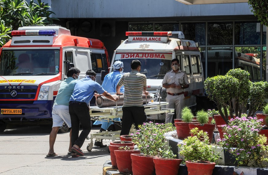 24.04.2021, Indien, Neu Delhi: Medizinische Mitarbeiter liefern einen Sauerstoffzylinder an das Jaipur Golden Krankenhaus, wo in der Nacht zuvor mindesten 25 Covid-19-Patienten wegen Sauerstoffmangel  ...