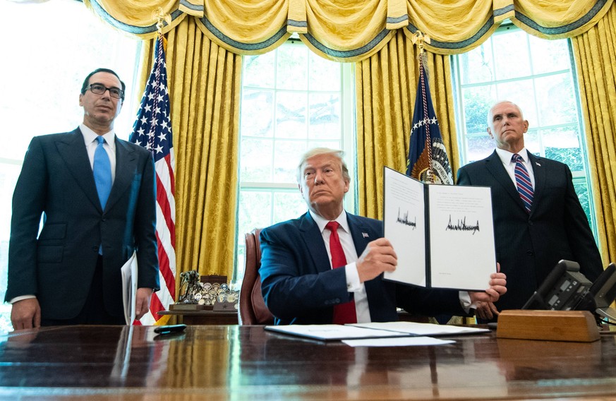 President Donald Trump, joined by Treasury Secretary Steven Mnuchin (L) and Vice President Mike Pence, holds up a copy of an executive order for additional sanctions against Iran and its leadership, a ...