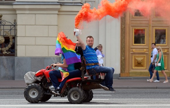 Gay and LGBT rights activist Nikolai Alexeyev (R) holds a flare as he rides a quad-bike during an unauthorized gay rights activists rally in central Moscow on May 30, 2015. Moscow city authorities tur ...