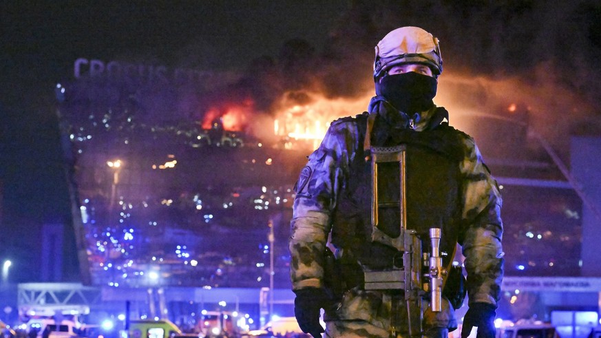 dpatopbilder - 22.03.2024, Russland, Moskau: Ein Soldat der russischen Nationalgarde (Rosgwardija) sichert ein Gebiet, während über Crocus City Hall am westlichen Rand Moskaus ein gewaltiger Brand zu  ...