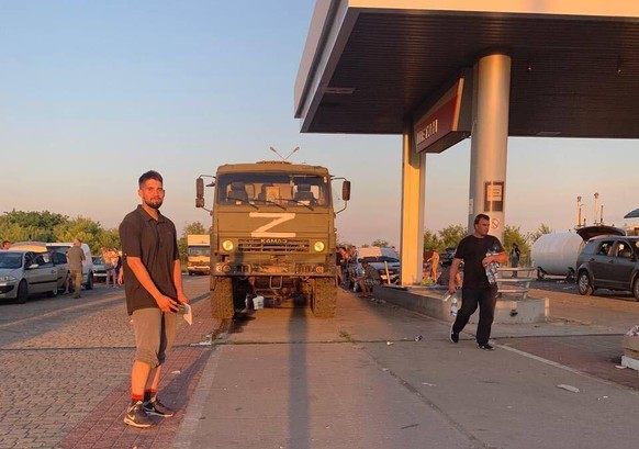 Yura an einer Tankstelle in Cherson. Hinter ihm steht ein russisches Militärfahrzeug.