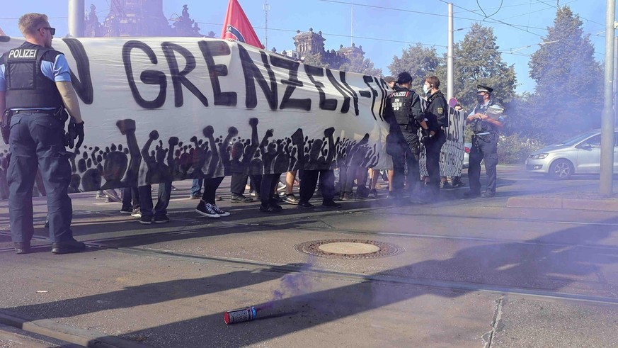 20.09.2020, Sachsen, Dresden: Ein Polizist versucht vor einem Transparent des Demonstrationszugs «Seebrücke» einen Nebeltopf auszutreten. (zu dpa «Polizist droht Demonstrant - Fall wird untersucht») F ...