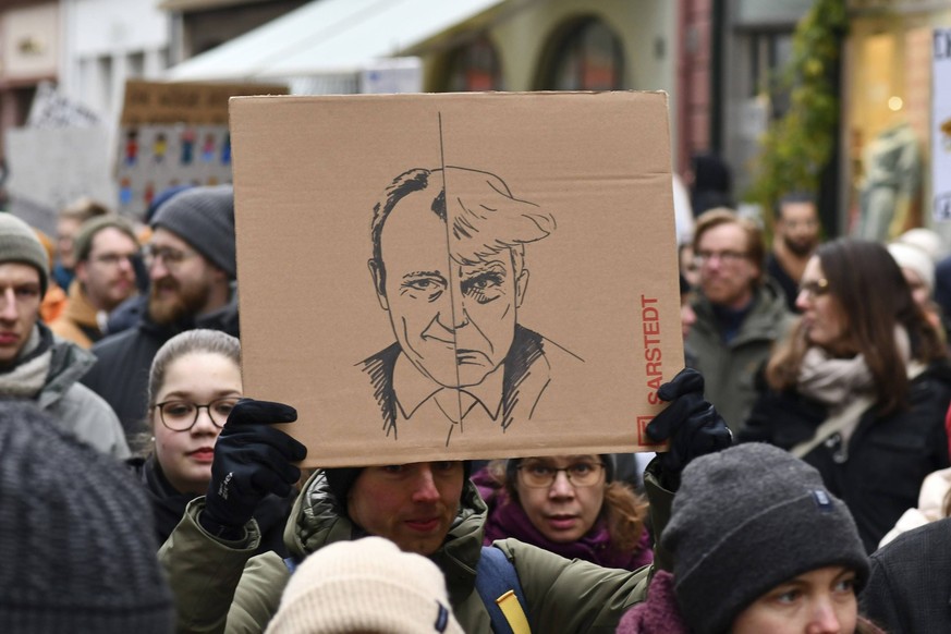 Heidelberg, Deutschland 12. Februar 2025: Person hält Schild hoch, auf dem der CDU Politiker Friedrich Merz mit dem US Präsidenten Donald Trump verglichen wird, in der Menge bei einer Demonstration ge ...