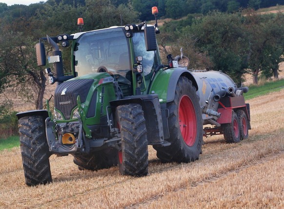 Landwirt waessert mit grossem Wasserfass eine Feld gegen Feldbrand. Bauer mit Wasserfass *** Farmer waters field with large water barrel against field fire Farmer with water barrel