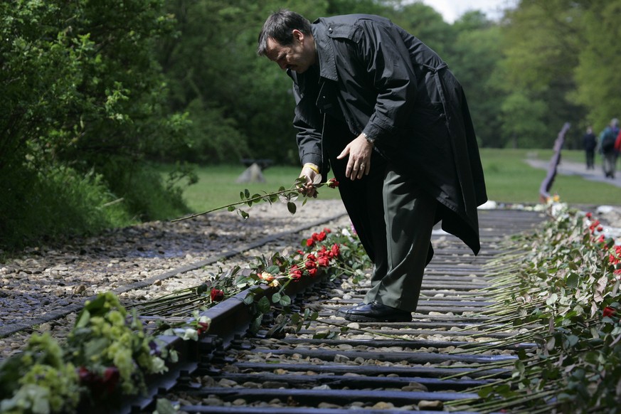 In this Monday May 9, 2015, file photo, a man puts a rose on the railroad tracks at former concentration camp Westerbork, the Netherlands, remembering more than a hundred thousand Jews who were transp ...