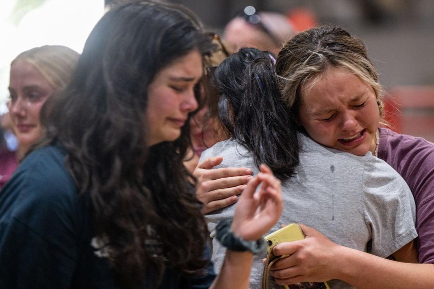 UVALDE, TEXAS - MAY 25: Community members mourn together at a vigil for the 21 victims in the mass shooting at Rob Elementary School on May 25, 2022 in Uvalde, Texas. Nineteen students and two adults  ...