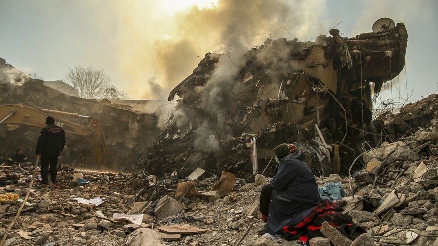 12.02.2023, Türkei, Kahramanmaras: Eine Frau sitzt neben einem eingestürzten Gebäude. Fast eine Woche nach der Erdbeben-Katastrophe im türkisch-syrischen Grenzgebiet ist die Zahl der Toten auf mehr al ...