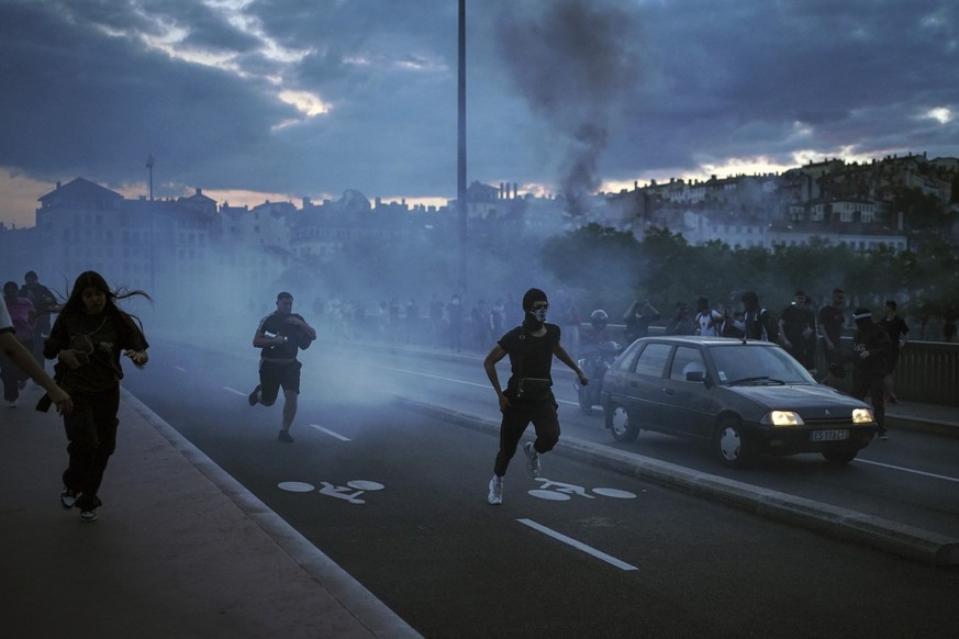 30.06.2023, Frankreich, Lyon: Menschen fliehen während es zu Zusammenstößen mit der Polizei kommt. Mit Einschränkungen des öffentlichen Lebens will die Regierung in Frankreich die schweren Krawalle na ...