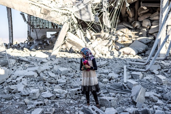 23.08.2023, Syrien, Idlib: Die 12-jährige Taima Al Khaled steht vor einem zerstörten Gebäude. Das Gebäude wurde bei einem russischen Luftangriff zerstört, der auf eine Wasserstation abzielte und bei d ...