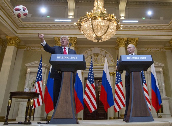 In this July 16, 2018, photo, U.S. President Donald Trump, left, tosses a soccer ball to his wife first lady Melania Trump after Russian President Vladimir Putin presented it to him during a news conf ...