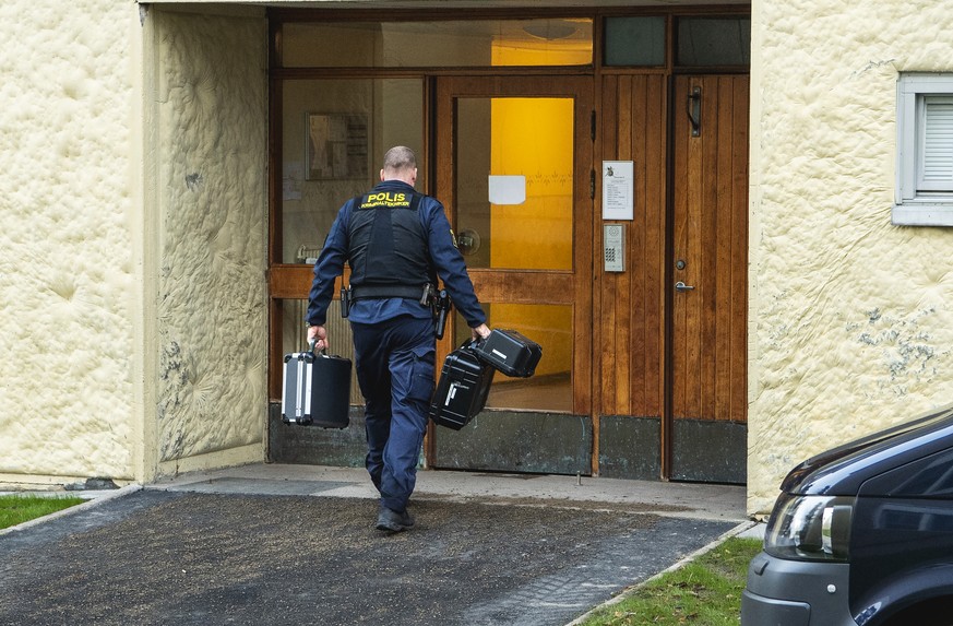 01.12.2020, Schweden, Stockholm: Ein Polizist geht auf den Eingang eines Mehrfamilienhauses in Haninge s