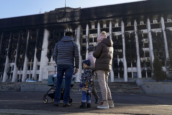 Eine Familie blickt auf die Schäden, die durch gewaltsame Zusammenstöße zwischen Demonstranten und Polizei im Januar 2022 in Almaty, Kasachstan, entstanden sind.