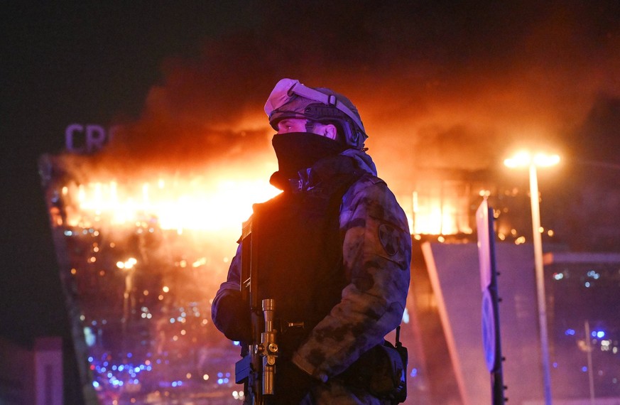Russia Terrorist Attack 8647807 22.03.2024 A law enforcement officer is seen near the burning Crocus City Hall concert venue following a reported shooting incident, near Moscow, Russia. Several gunmen ...