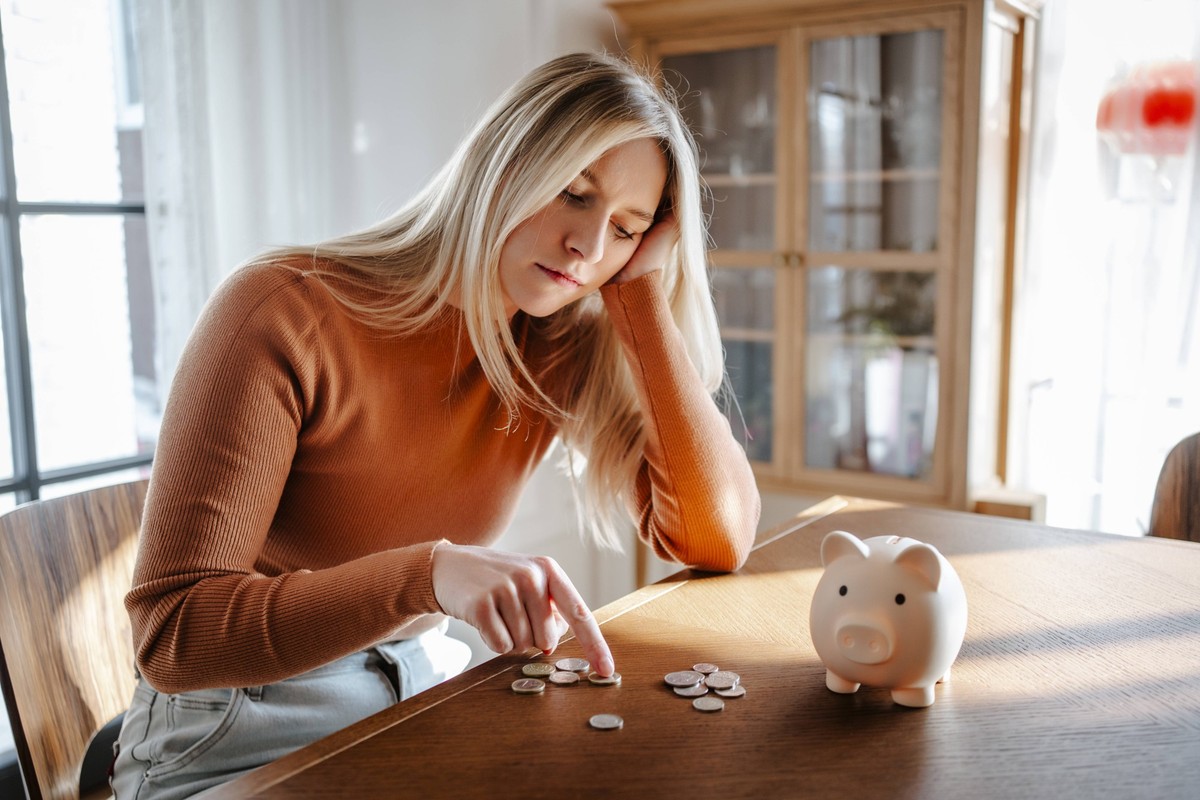 Woman contemplating savings with piggy bank and coins at home model released, Symbolfoto property released, MDOF02805