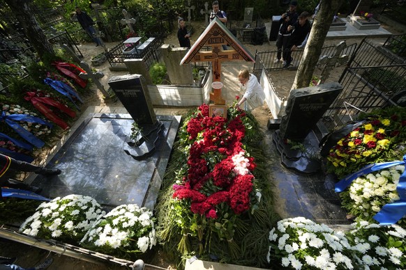 dpatopbilder - 30.08.2023, Russland, St. Petersburg: Eine Frau legt Blumen auf ein Grab auf dem Friedhof Porochowskoje. Der russische Söldnerführer Jewgeni Prigoschin ist nach Angaben seines Pressedie ...