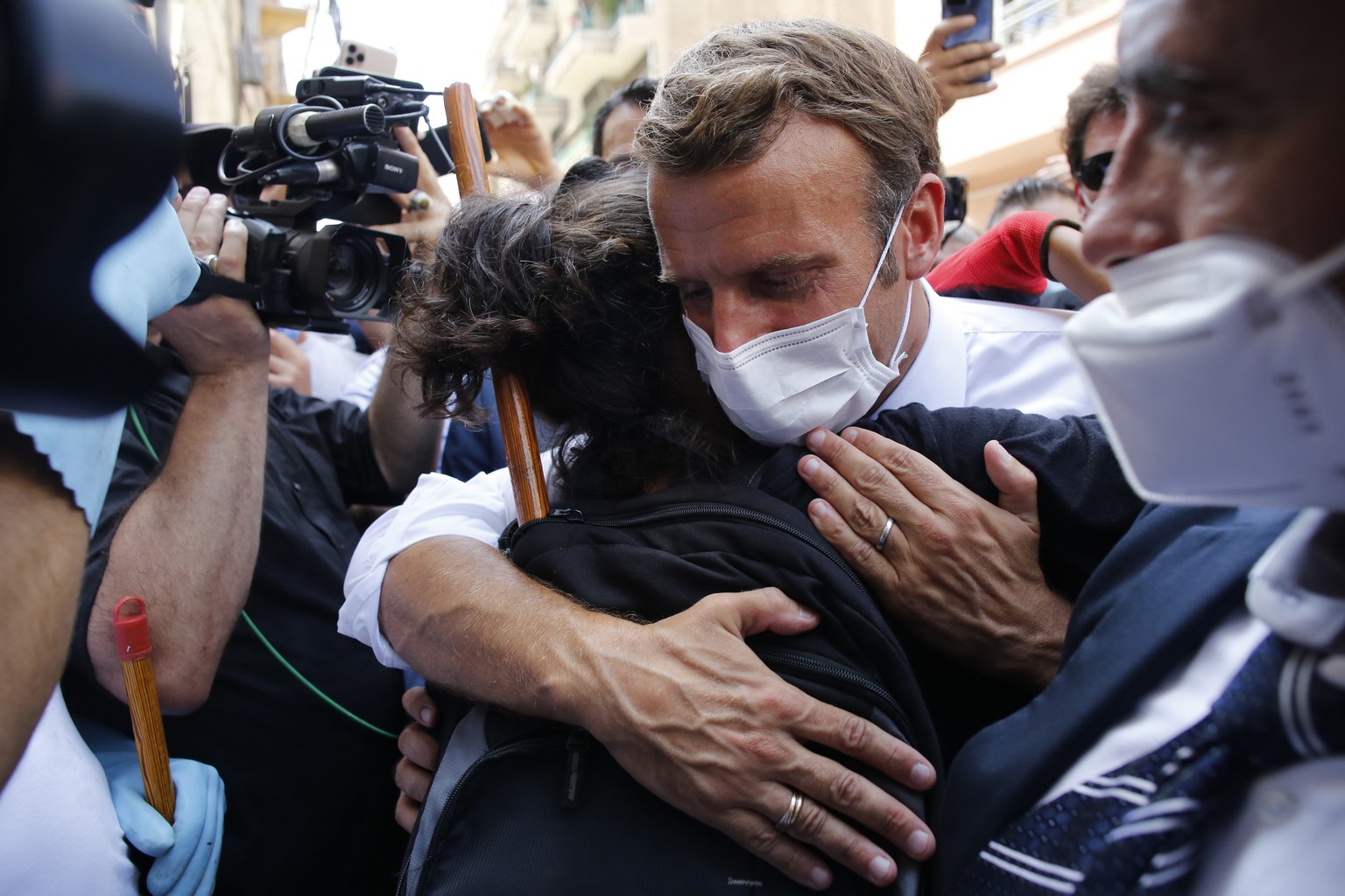 French President Emmanuel Macron hugs a resident as he visits a devastated street of Beirut, Lebanon, Thursday Aug.6, 2020. French President Emmanuel Macron has arrived in Beirut to offer French suppo ...