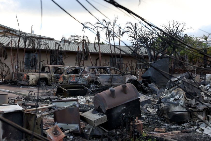 LAHAINA, HAWAII - AUGUST 16: Burned cars sit in front of a home that was destroyed by a wildfire on August 16, 2023 in Lahaina, Hawaii. At least 106 people were killed and thousands were displaced aft ...