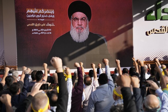 dpatopbilder - 03.11.2023, Libanon, Beirut: Anhänger der vom Iran unterstützten Hisbollah erheben ihre Fäuste und jubeln, als Hisbollah-Führer Hassan Nasrallah während einer Kundgebung zum Gedenken an ...