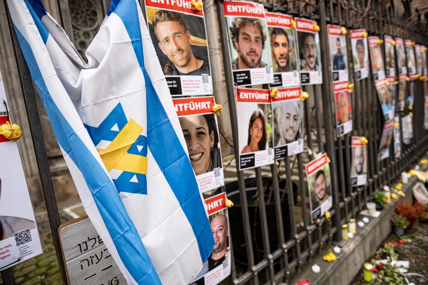 16.01.2025, Israel, Tel Aviv: Bilder der von Hamas entführten Geiseln hängen am Zaun vor der Neuen Synagoge Berlin. Nach einem mehr als 15 Monate langen Krieg im Gazastreifen haben sich Israel und die ...