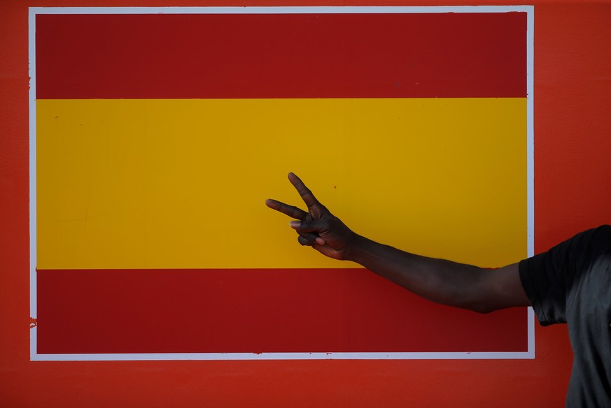 A migrant, intercepted aboard a dinghy off the coast in the Strait of Gibraltar, gestures next to a Spanish flag on a rescue boat after arriving at the port of Algeciras, southern Spain July 22, 2018. ...