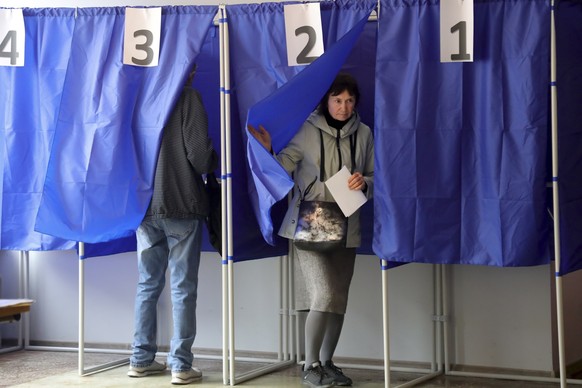 A woman holds her ballot as she leaves a voting booth during a referendum in at a polling station in Mariupol, Donetsk People's Republic controlled by Russia-backed separatists, eastern Ukraine, Tuesd ...