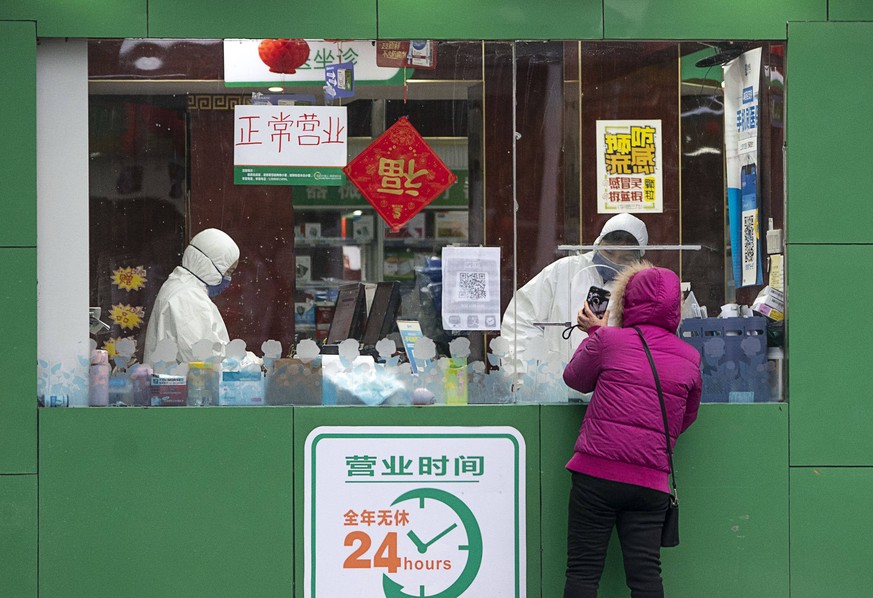 Eine Bewohnerin Wuhans deckt sich vor einer Apotheke mit Medikamenten ein.