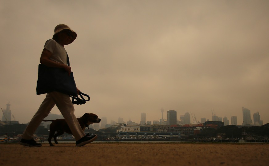 SYDNEY SMOKE HAZE, A woman walks her dog in Blackwattle bay as smoke haze from bushfires in New South Wales blankets the CBD in Sydney, Tuesday, December 10, 2019. ACHTUNG: NUR REDAKTIONELLE NUTZUNG,  ...