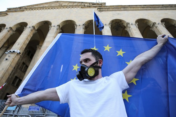 17.04.2024, Georgien, Tiflis: Ein Demonstrant hält eine EU-Flagge, während eiener Demonstration vor dem Parlamentsgebäude. Trotz anhaltender Proteste hat das Parlament in der Südkaukasusrepublik Georg ...