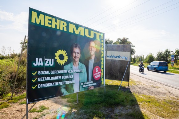 ARCHIV - 14.08.2024, Brandenburg, Hohen Neuendorf: Ein Wahlplakat der Brandenburger Grünen am Ortsausgang von Hohen Neuendorf. Letzten Dienstsag war ein Wahlhelfer der Grünen beim Verteilen von Wahlwe ...