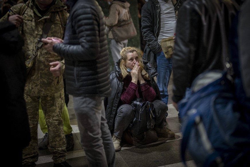 dpatopbilder - 24.02.2022, Ukraine, Kiew: Eine Frau sitzt auf ihrem Gep�ck, w�hrend sie am Bahnhof darauf wartet die Stadt verlassen zu k�nnen. Russische Truppen haben ihren erwarteten Angriff auf die ...
