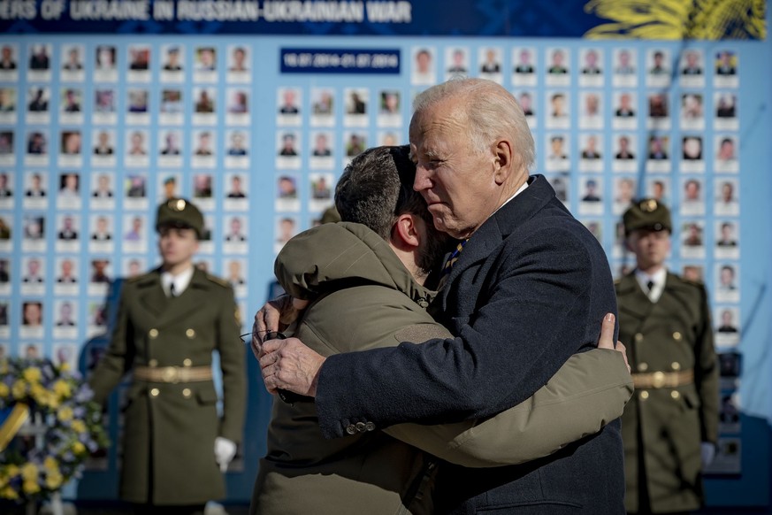 HANDOUT - 20.02.2023, Ukraine, Kiew: Joe Biden (Mitte r), Präsident der USA, und Wolodymyr Selenskyj, Präsident der Ukraine, umarmen sich zum Abschied an der Gedenkmauer für die gefallenen Verteidiger ...